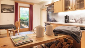 A cozy room with a wooden table, two white mugs, a book, and a grey blanket. - Haus Alpenkönig  (Neustift Im Stubaital)