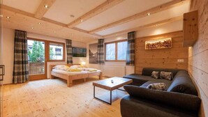 A wooden interior with a bed, sofa, and a small table. - Haus Alpenkönig  (Neustift Im Stubaital)