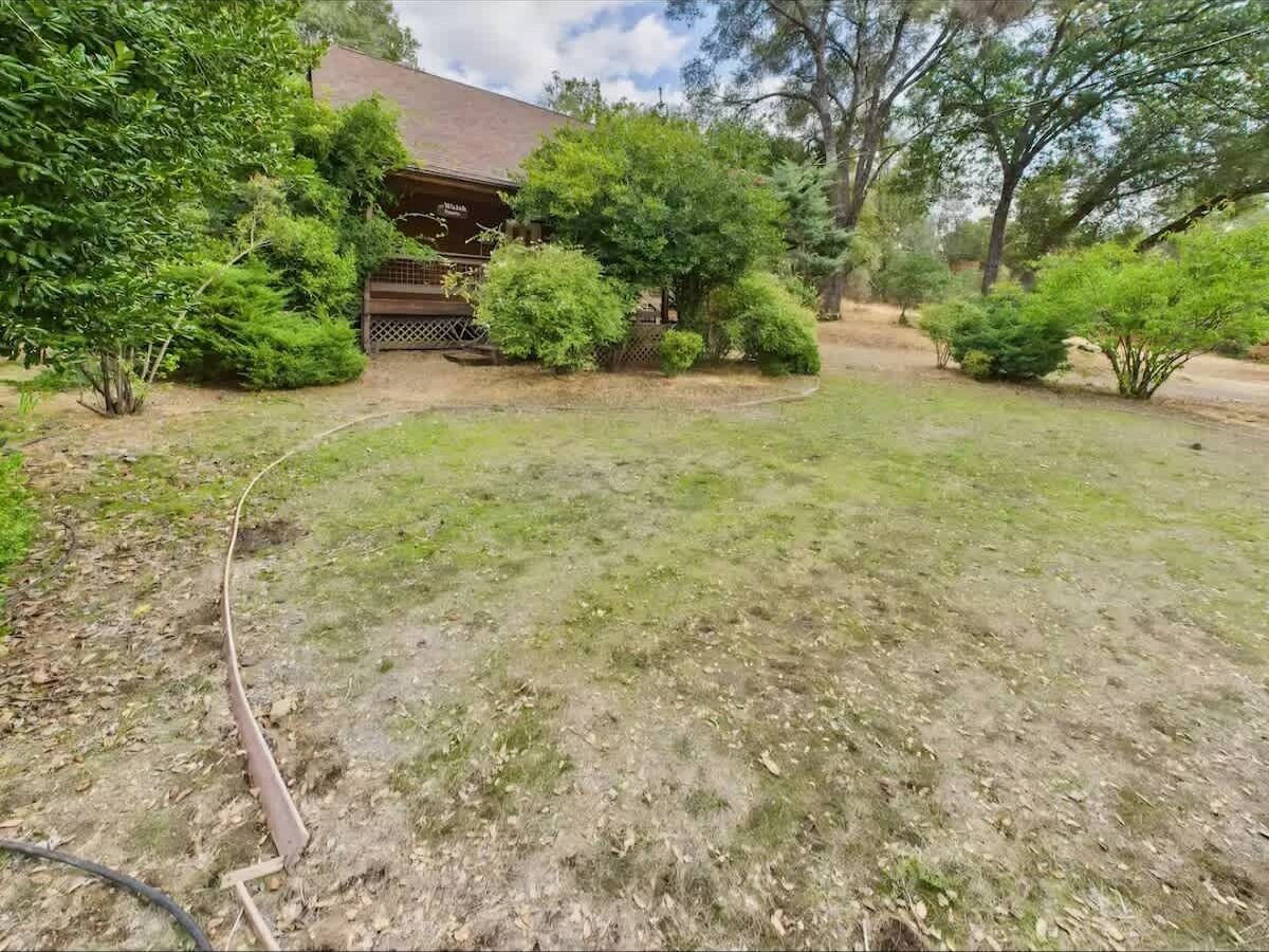 A residential property with a lawn, a wooden deck, and a house with a sloped roof.