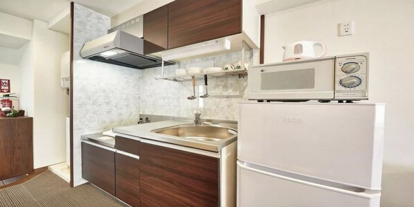 A compact kitchen with a microwave, sink, and built-in oven. - Hotel Cuore Kokusai Dori Naha (Naha)