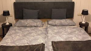 En dobbeltseng med sengetæppe med bladmotiv, to sengeborde med lamper, og en væg med runde dekorationer.