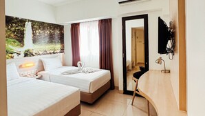 A hotel room with two beds, a desk, a chair, a TV, and an air conditioning unit. - The Himana Hotel Malang (Malang)