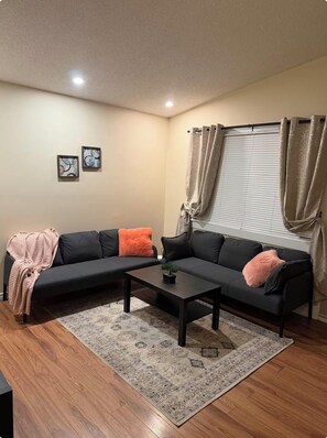 A living room with a sectional sofa, a coffee table, and a rug. - Gorgeous Beacon Heights 2 bedrooms apartment (Edmonton)