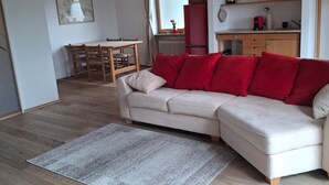 A living room with a sofa, a dining table, and a kitchen area. - Cozy vacation apartment 70sqm for max. 4 persons with terrace (Laufen)