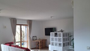 A living room with a sofa, a wooden table, a TV, and a white shelving unit. - Cozy vacation apartment 70sqm for max. 4 persons with terrace (Laufen)