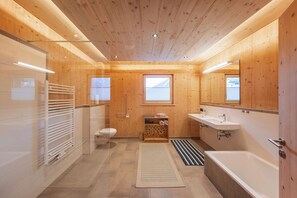 Een moderne badkamer met houten wanden, een badkuip, een toilet en een wastafel.