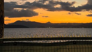 A sunset view over a body of water with a palm tree and a distant mountain range. - La Kaz by Kaz Kafe (Pamandzi)