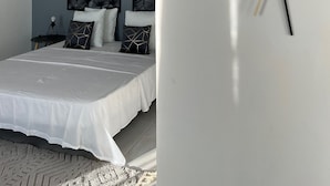 A bedroom with a bed, pillows, a nightstand, and wall art. - La Kaz by Kaz Kafe (Pamandzi)