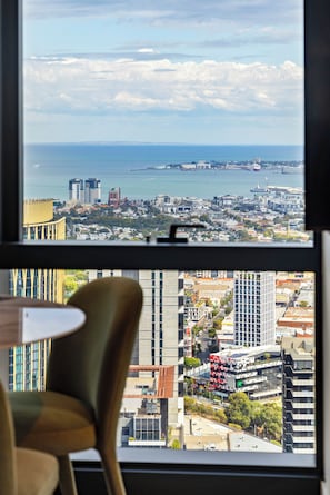 Blick auf eine Stadtlandschaft durch ein Fenster, inklusive Gebäude, eines Gewässers und eines Stuhls.