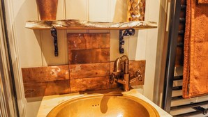 A bathroom with a wooden vanity, copper faucet, and a sink. - Twit Twoo Shepherds Hut (Louth)