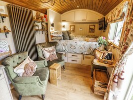 Una habitación acogedora con una cama, un sillón verde, una mesita de madera y un pequeño cofre de madera.