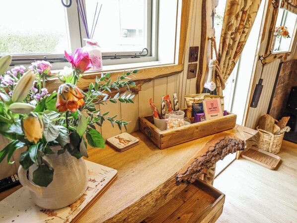 Une table en bois ornée d’un vase de fleurs, d’un panier de collations et d’une pancarte de bienvenue.