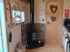 Una habitación acogedora con chimenea, paredes de madera, una decoración con forma de corazón y una ventana con flores.