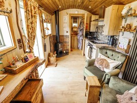 A cozy room with a fireplace, wooden furniture, and a kitchen area.