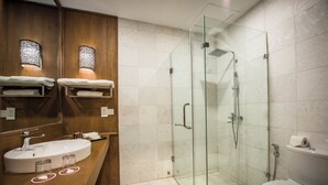 A modern bathroom with a glass-enclosed shower, a wooden vanity with a sink, and a toilet. - Royal Palace Hotel (Nyaung-U)