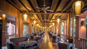 A long corridor with wicker furniture, ceiling fans, and hanging lanterns. - Royal Palace Hotel (Nyaung-U)
