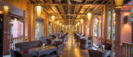 A long corridor with wicker furniture, ceiling fans, and hanging lanterns.