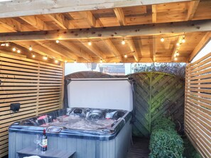 A hot tub with a wooden deck, string lights, and a wooden fence. - Crescent Bay House (Filey)