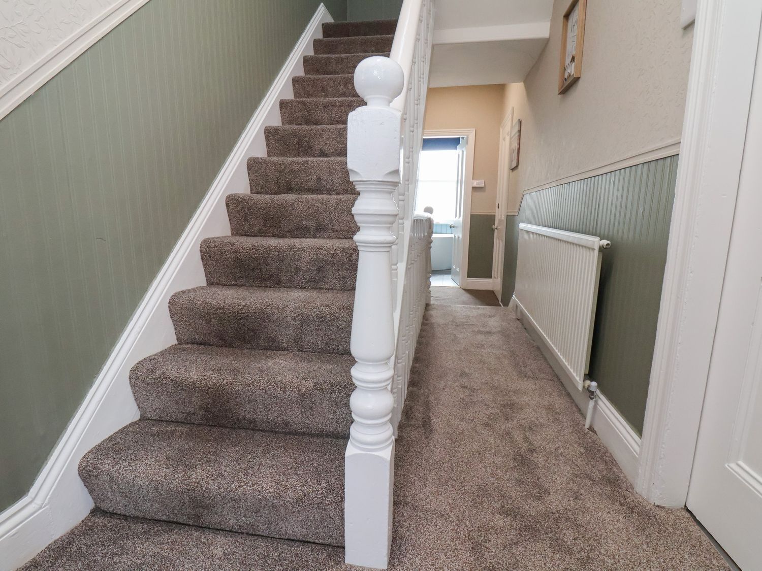 Un escalier avec des marches recouvertes de moquette et une balustrade blanche.