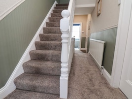 Una escalera con peldaños alfombrados y barandilla blanca.