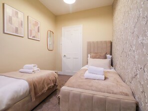 A hotel room with two beds, a door, and two framed artworks on the wall. - Crescent Bay House (Filey)