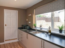 Una cocina con ventana, puerta y encimera con tostadora y planta.
