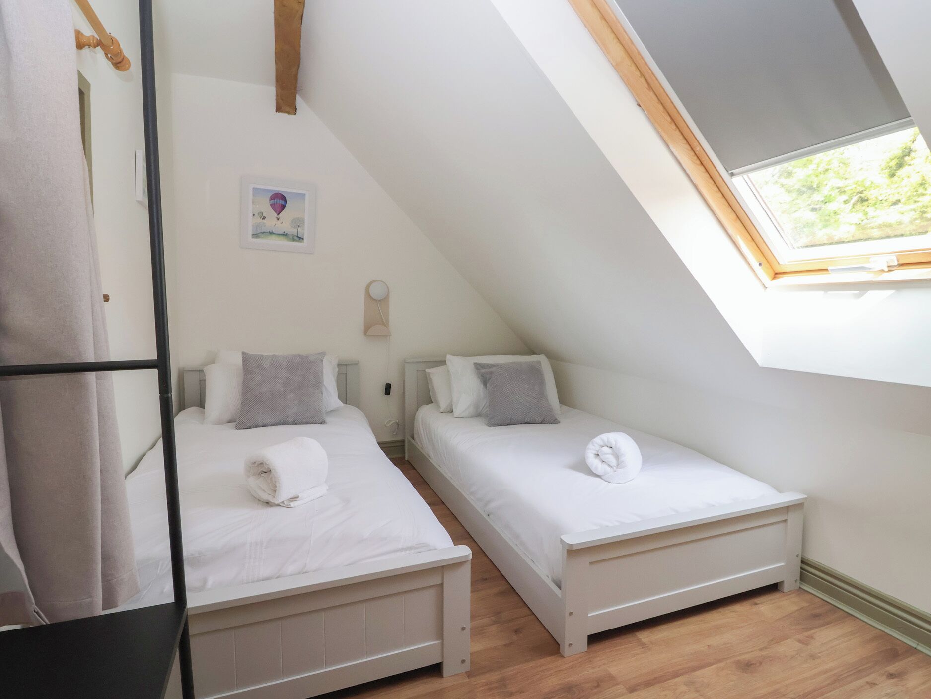 Una habitación pequeña y moderna con dos camas, un tragaluz y un diseño sencillo y limpio.