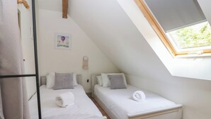 Une petite chambre moderne avec deux lits, une lucarne et un aménagement simple et épuré.
