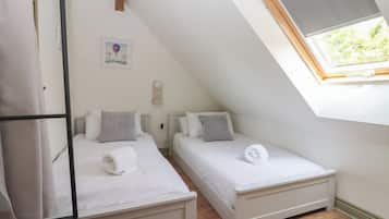 Una habitación pequeña y moderna con dos camas, un tragaluz y un diseño sencillo y limpio.