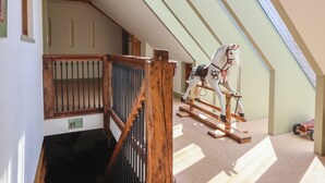 Une pièce avec un plafond en pente, un cheval à bascule en bois et une fenêtre.