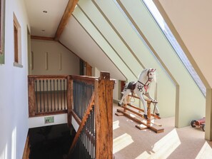 A room with a sloped ceiling, a wooden rocking horse, and a window. - Redwoods (Beverley)