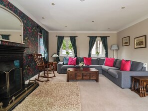 Una sala de estar con chimenea, un conjunto de sofá, un sillón mecededor y una mesa de centro.