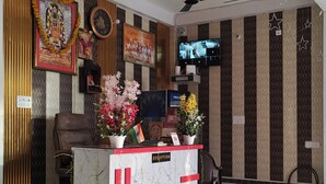 Een receptiegedeelte met een receptiebalie, een plafondventilator, een televisie en decoratieve wandpanelen.