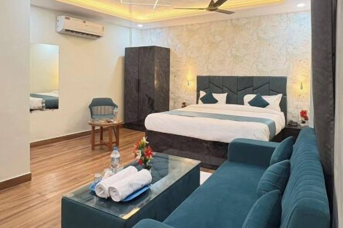 A modern hotel room with a bed, sofa, and a small table with towels.