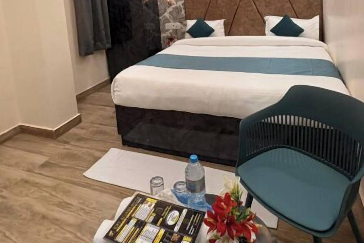 A modern hotel room with a bed, ceiling fan, and a small table with a chair.