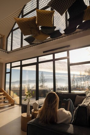Ein modernes Interieur mit großen Fenstern, einer Treppe und einer Couch mit einem Buch.