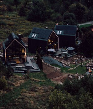 Ein modernes, freistehendes Haus mit einer großen Terrasse, einer Feuerstelle und einem gepflegten Garten.