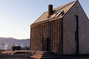 A modern wooden cabin with a sloped roof, a chimney, and a small porch with steps leading to the entrance. - FlowFort View Private HotTub & Sauna Dom Swobodnie (Wojcieszyce)