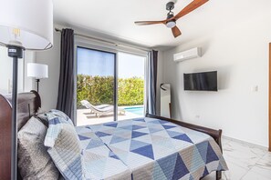 A bedroom with a bed, a ceiling fan, a TV, and a view of a pool. - Luxurious Villa with Private Pool in Sosua (Sosúa)
