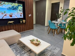 A modern living room with a TV, sofa, coffee table, and dining area with chairs. - Beautiful 05 Apartment in the Hearth of Playa del Carmen (Playa del Carmen)