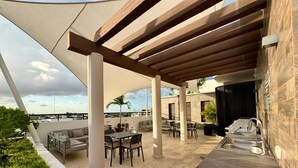 Une terrasse sur le toit, avec des sièges extérieurs, un barbecue et une vue sur les toits de la ville.