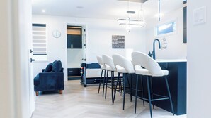 Eine moderne Küche mit Barbereich, weißen Barhocker und einer blauen Arbeitsplatte.
