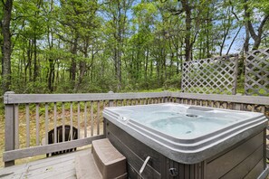 A hot tub on an outdoor deck with a wooden railing and a view of a forested area. - Summer fun at camelback • Hot Tub & Pool (Jackson Township)
