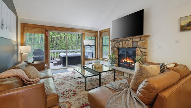 Una sala de estar con chimenea, sofás de cuero, una mesa de centro y un televisor montado en la pared.