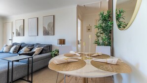 Een moderne woonkamer met een bank, een ronde tafel met placematen, een spiegel en lijstwerken aan de muur.