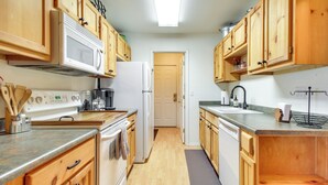 Une cuisine avec des meubles de rangement en bois, un four à micro-ondes, un réfrigérateur, une cuisinière et un évier.