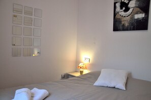 A hotel room with a bed, a nightstand with a lamp, a wall with multiple mirrors, and a painting. - Apartamento Cosmico. (Tarifa)