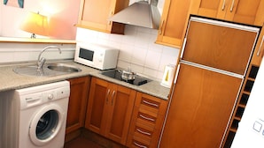 Eine kleine Küche mit Waschmaschine, Mikrowelle und Kühlschrank.