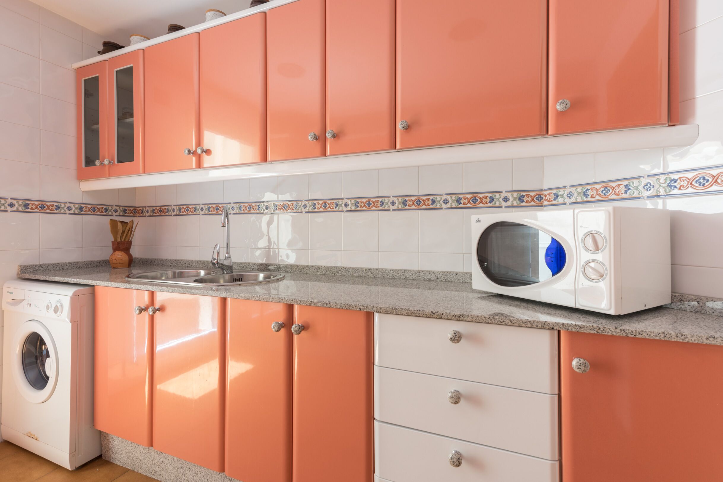A kitchen with a washing machine, a microwave, and a sink.