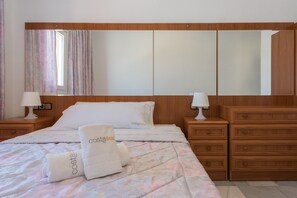 A hotel room with a bed, two nightstands, a dresser, a large mirror, and a window with curtains. - Puerto Bahía House . (Tarifa)